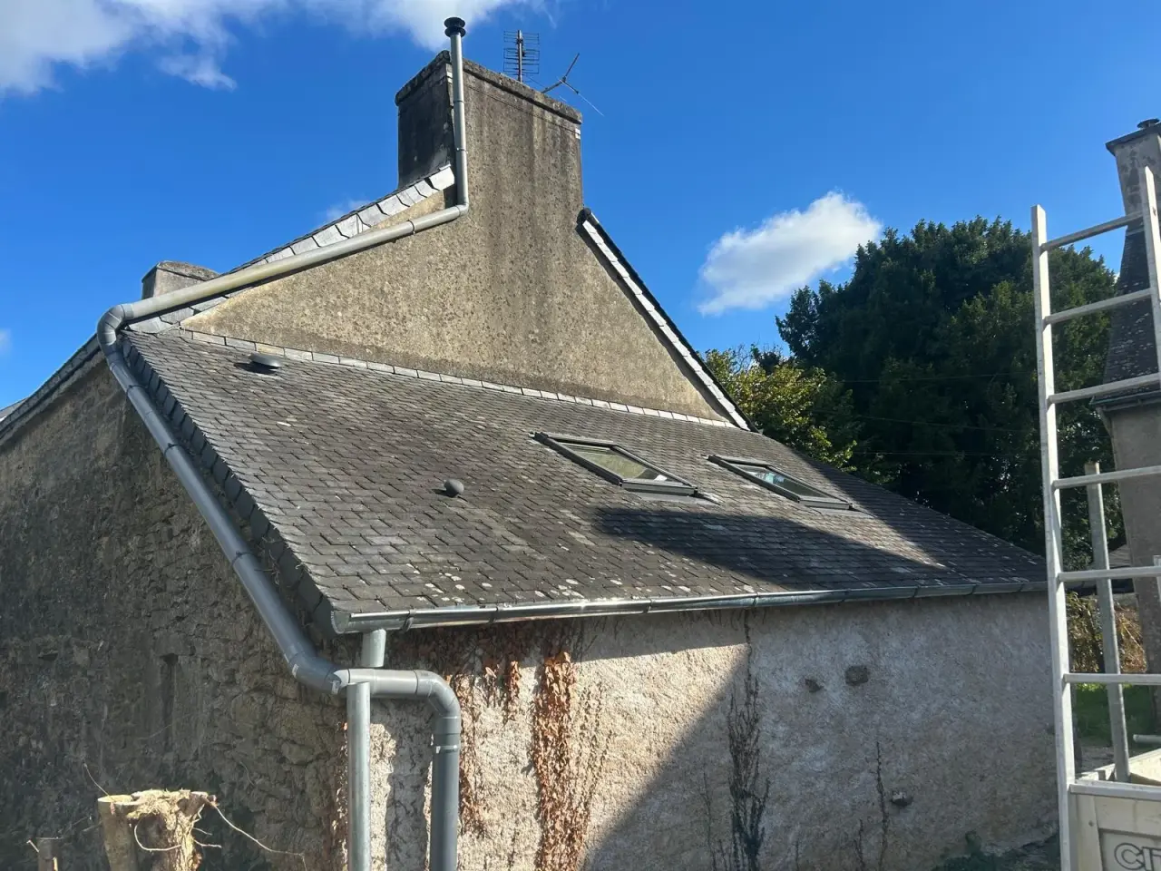 Gouttière neuve posée en rive de toiture, cheminée en arrière-plan