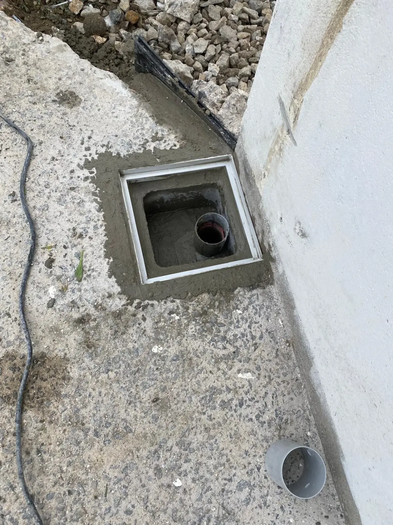 Regard scellé au mortier au pied d'un mur, avant pose de la grille