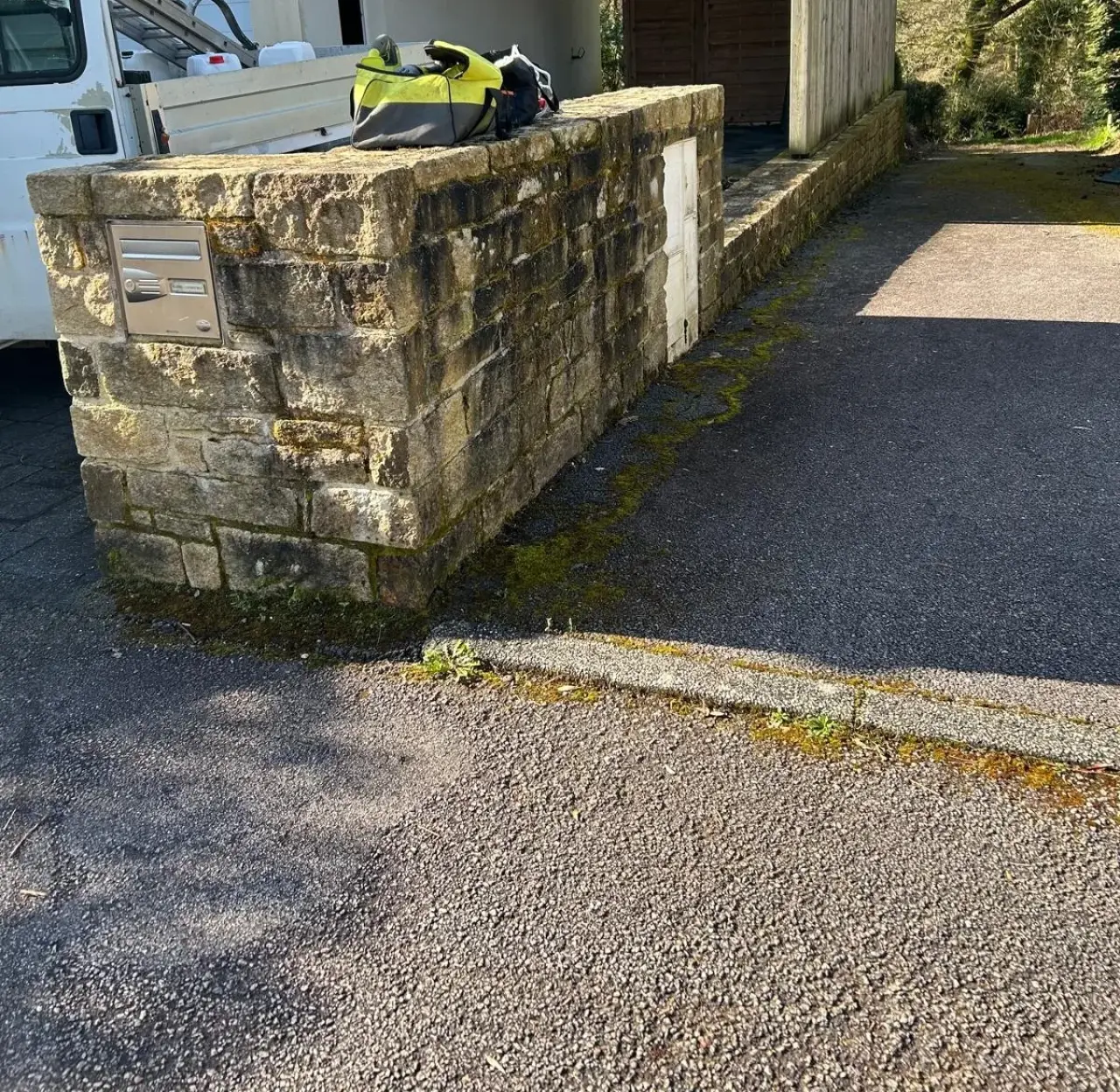 Mur en granit noirci par la mousse et les salissures, avant nettoyage