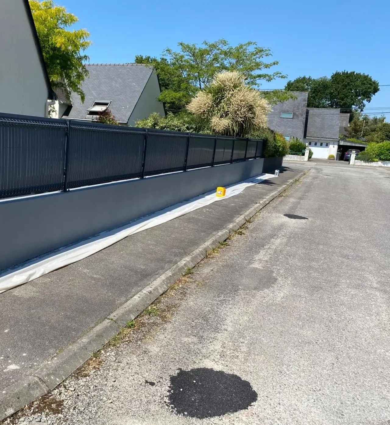 Le même mur de clôture en gris anthracite uniforme, après reprise