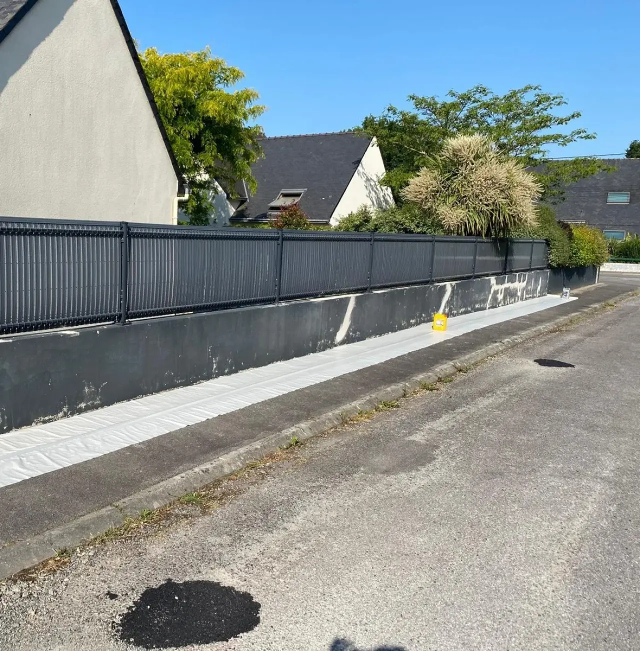 Mur de clôture en cours de reprise, taches claires de l'ancien revêtement encore visibles