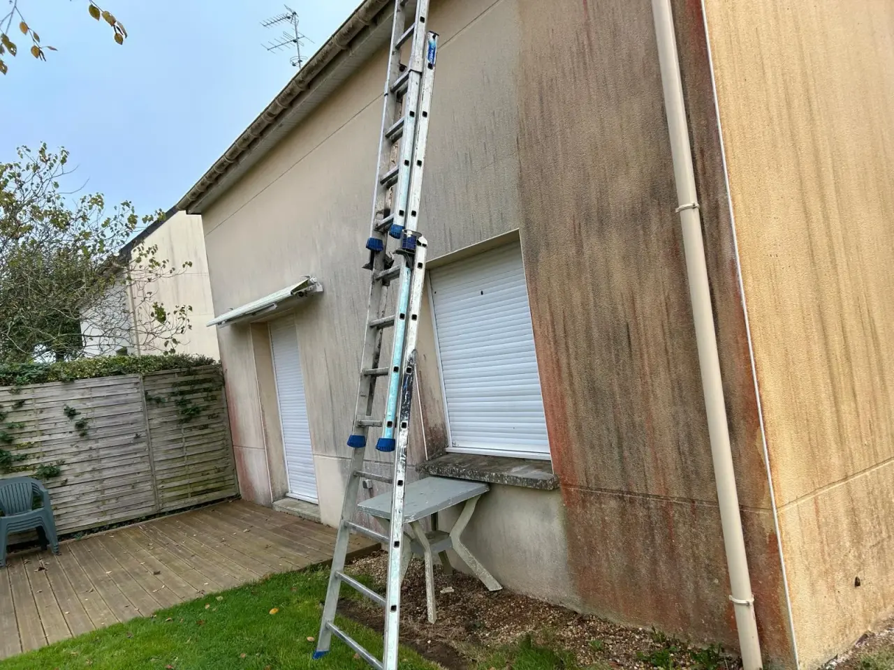 Mur latéral de maison marqué de coulures sombres, avant ravalement
