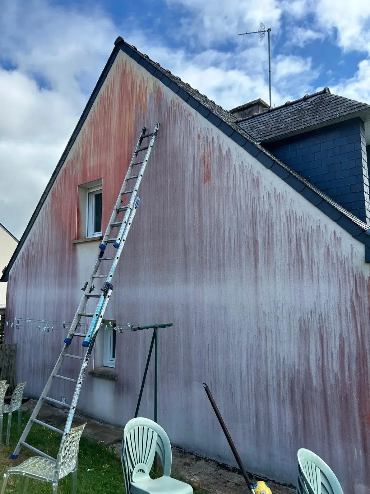 Pignon de maison strié de coulures brunes sur toute sa hauteur, avant ravalement